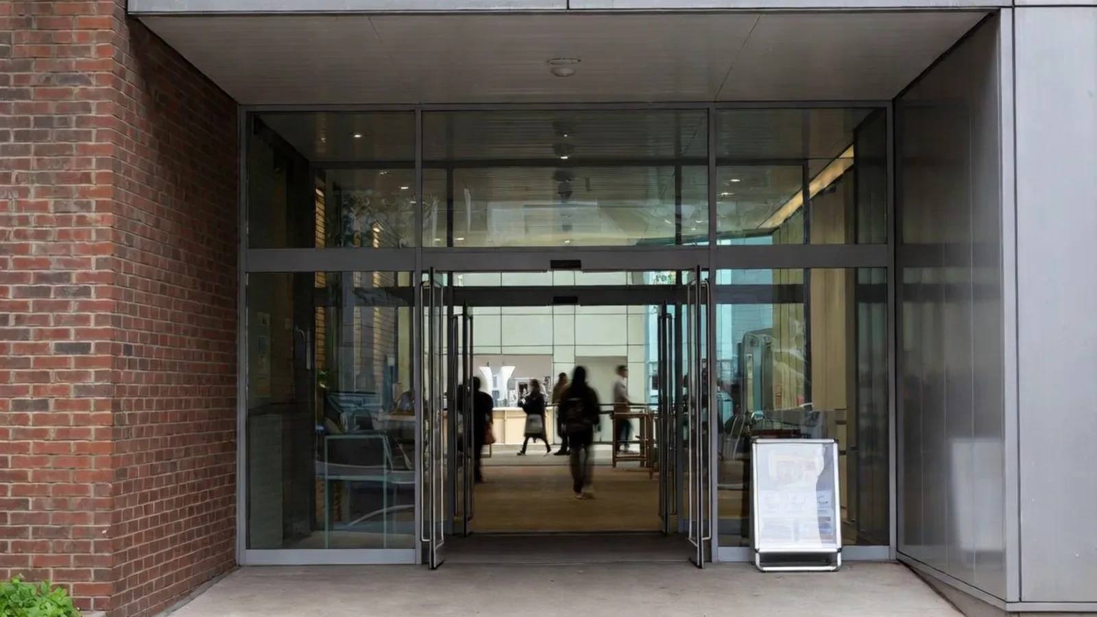 Modern glass entrance with brick and people