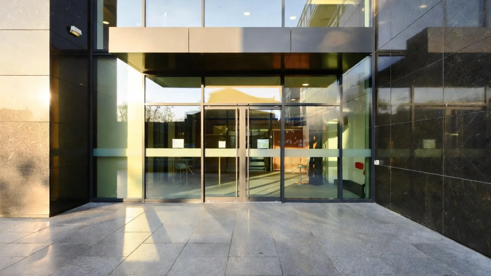 Modern office entrance with glass doors and dark stone