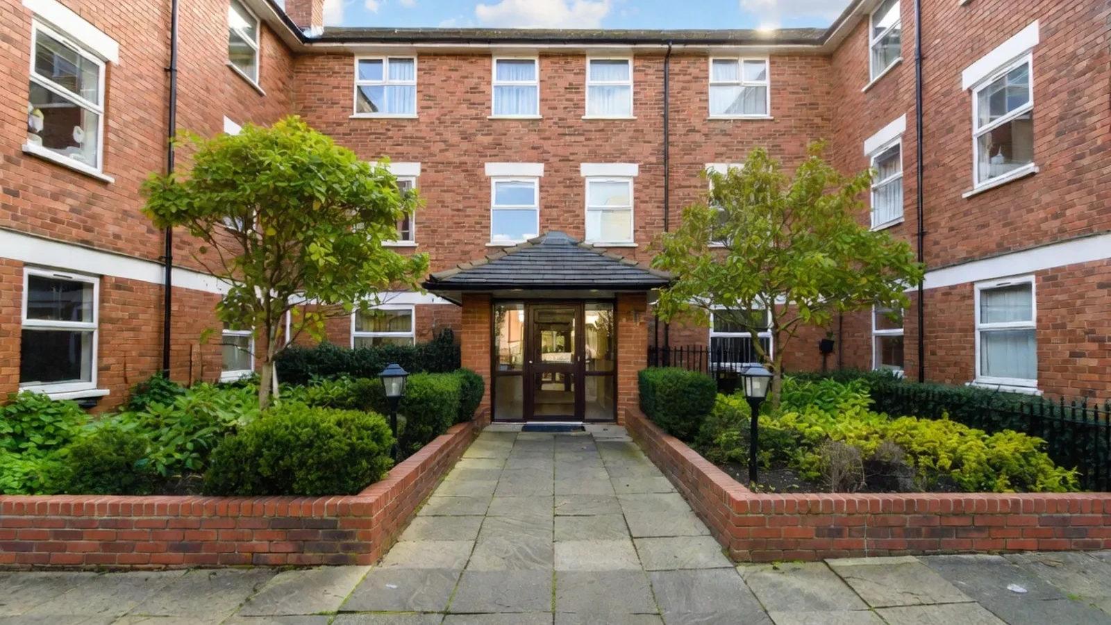 Brick residential courtyard with central path and green entrance