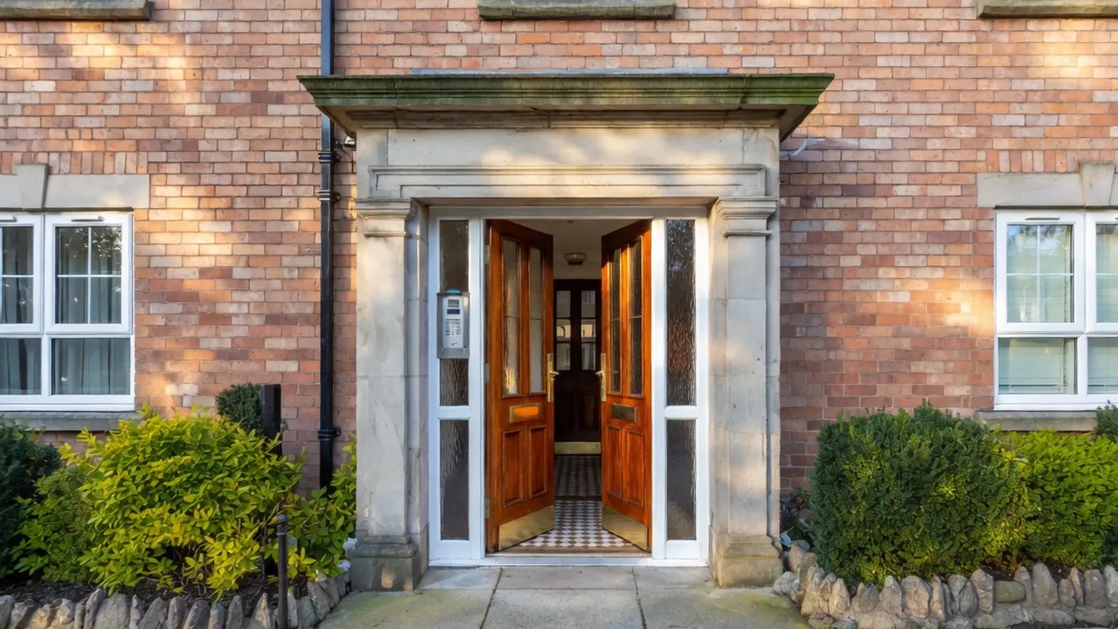 Brick apartment entrance with wooden doors and stone frame